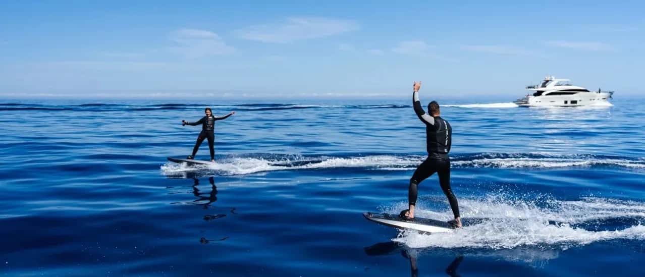 Two men are surfing on a blue ocean.