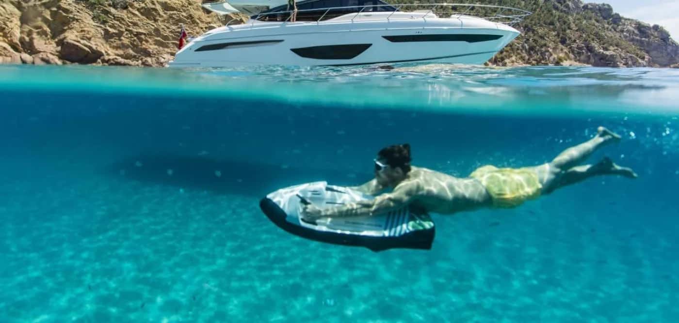 A man is swimming on a electric scooter under the ocean.