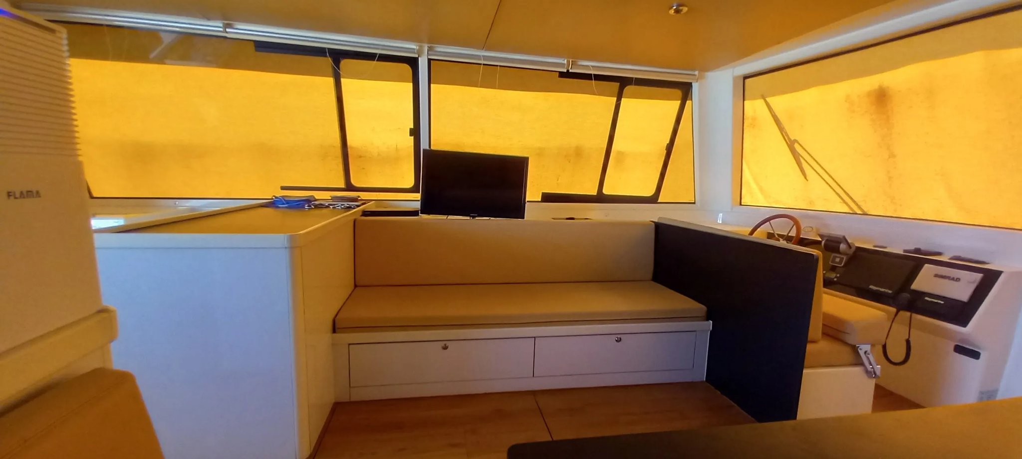 Un bote blanco con un banco negro y un televisor en la pared.