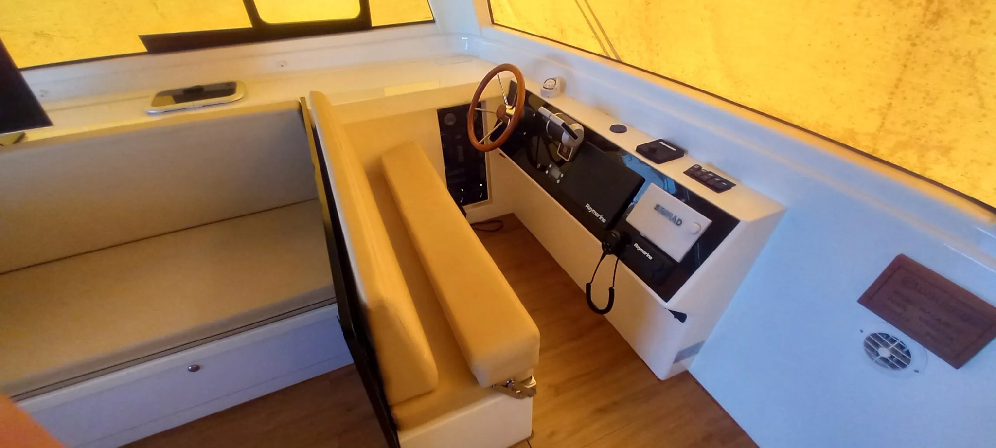 Un bote blanco con un asiento marrón y una rueda de dirección.