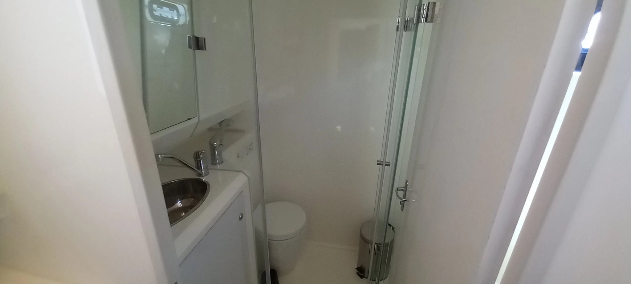 Un baño blanco con un inodoro y una ducha.