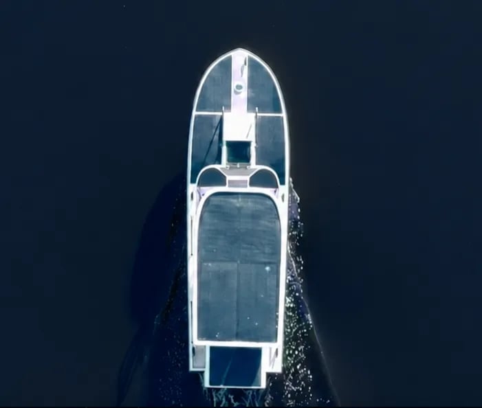 Top-down aerial view of the Elvene Amber solar-electric boat crossing deep blue water.