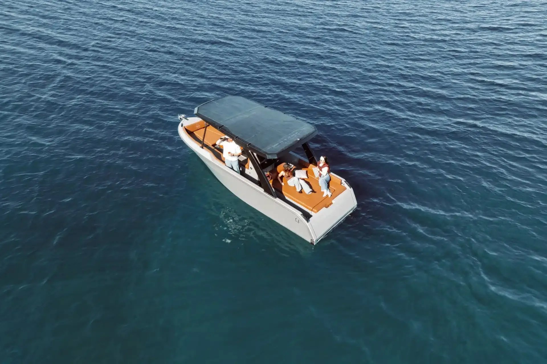 Aerial view of the Helios Omega electric boat with passengers relaxing on the water.