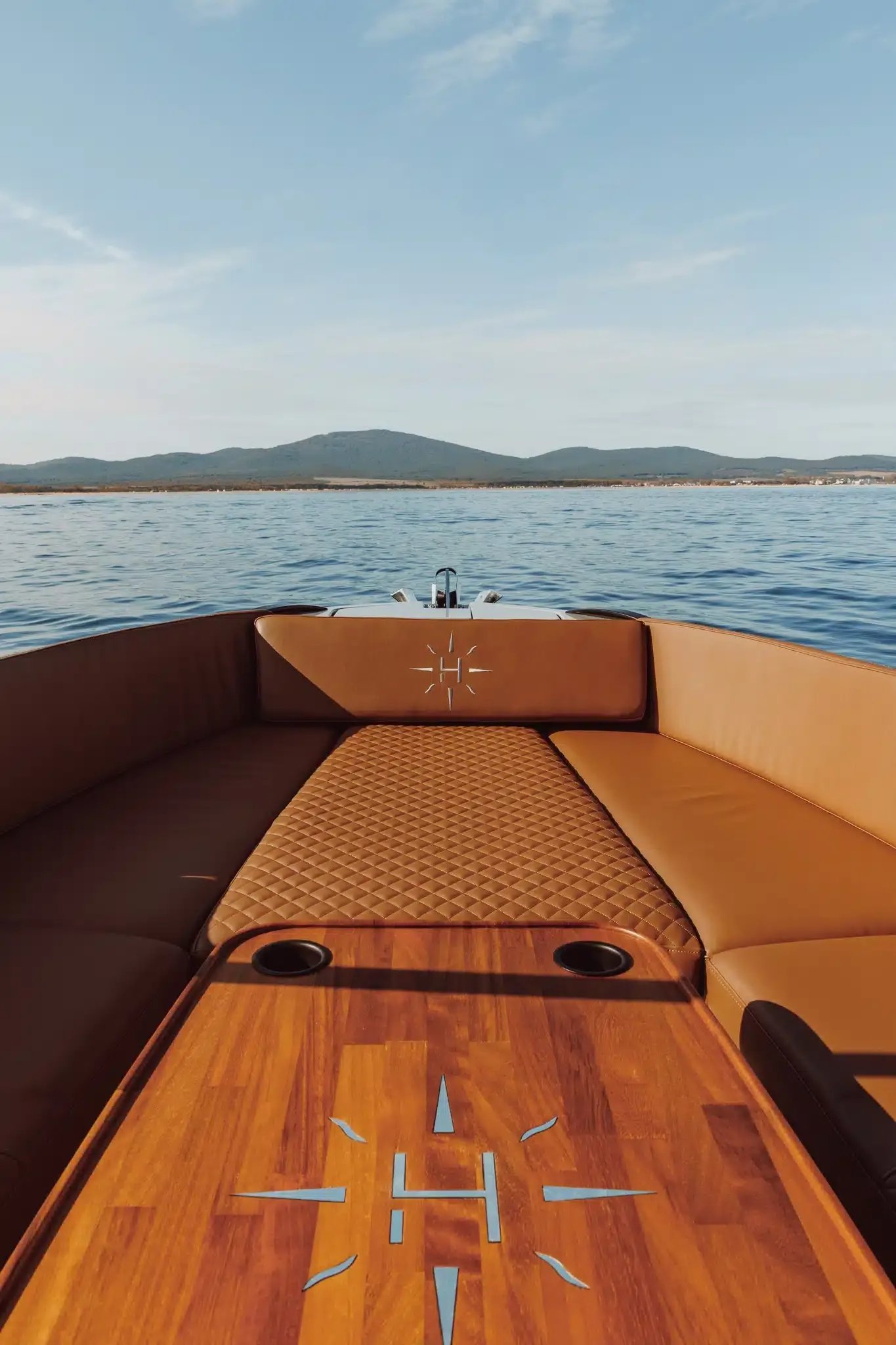 Bow sunbed and wooden table aboard the Helios Omega electric boat.