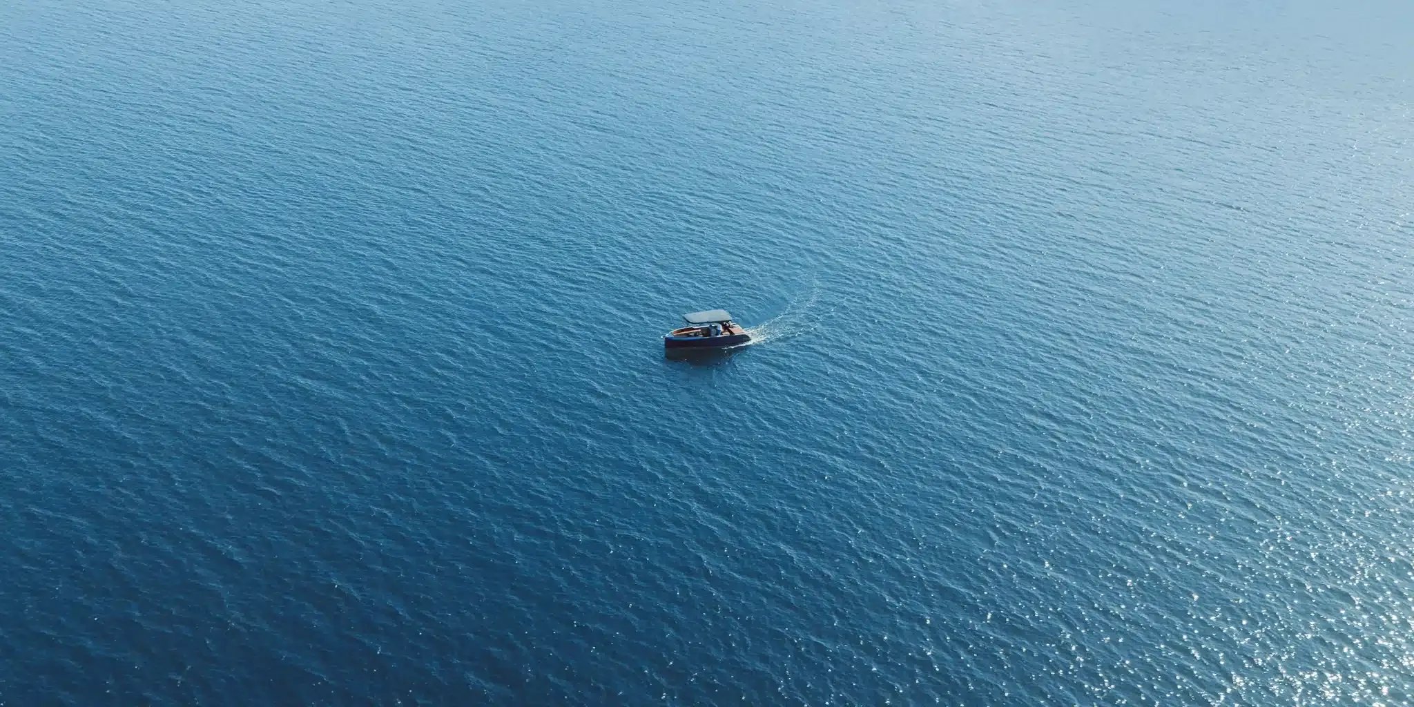 Aerial view of the Helios Omega electric boat cruising across open water.