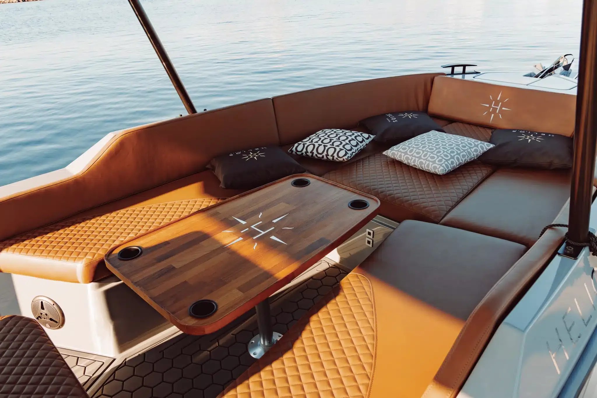 Helios Omega electric boat seating area with quilted upholstery and a wooden table.