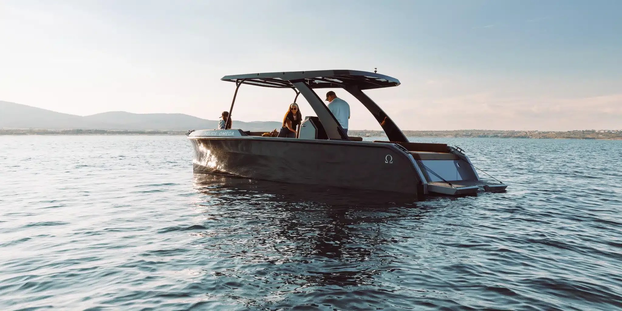 Side view of the Helios Omega electric boat with passengers aboard on calm water.
