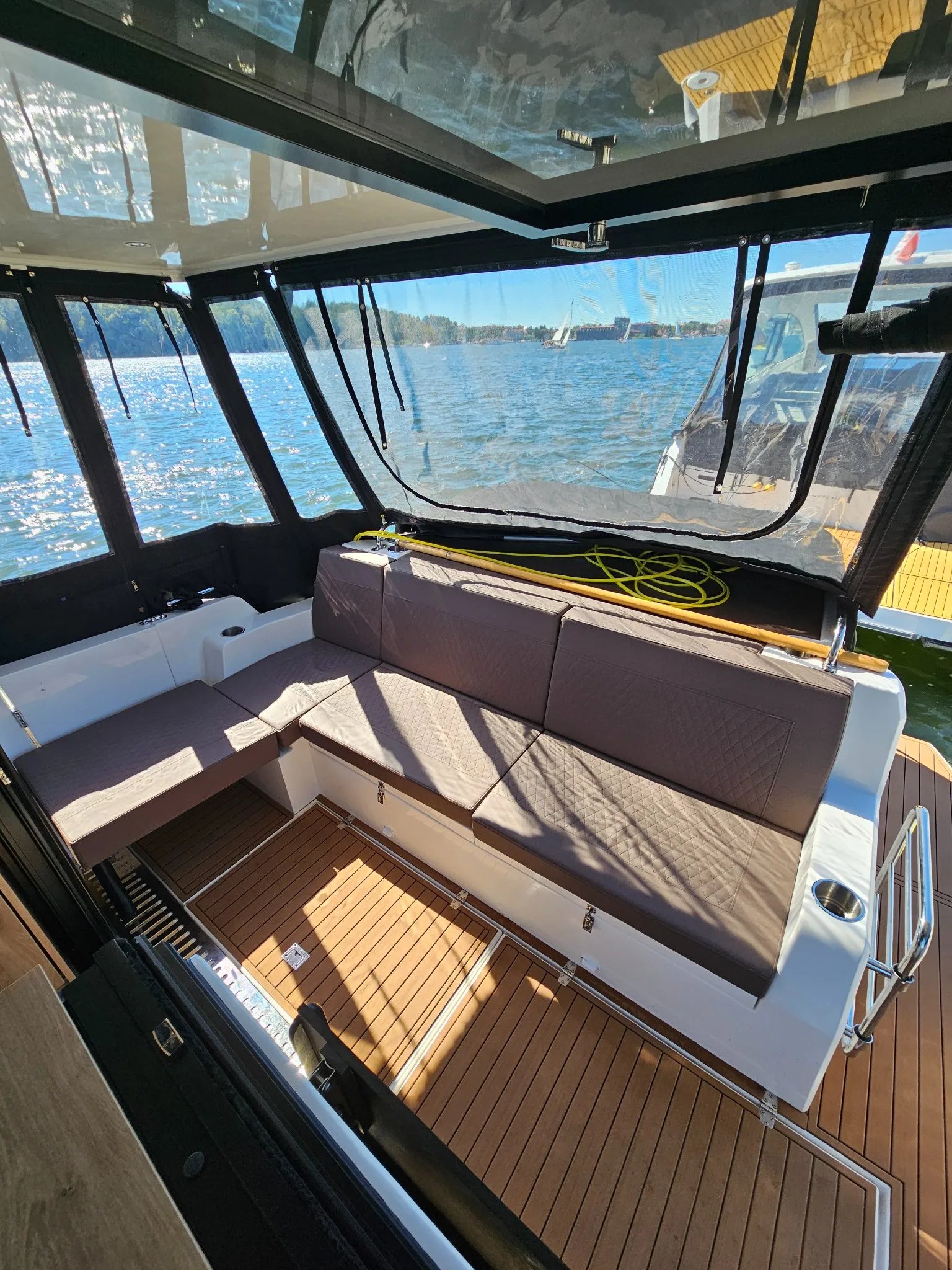 Covered aft cockpit of the Lamdo eLY30+ with an L-shaped seating area and open water views.