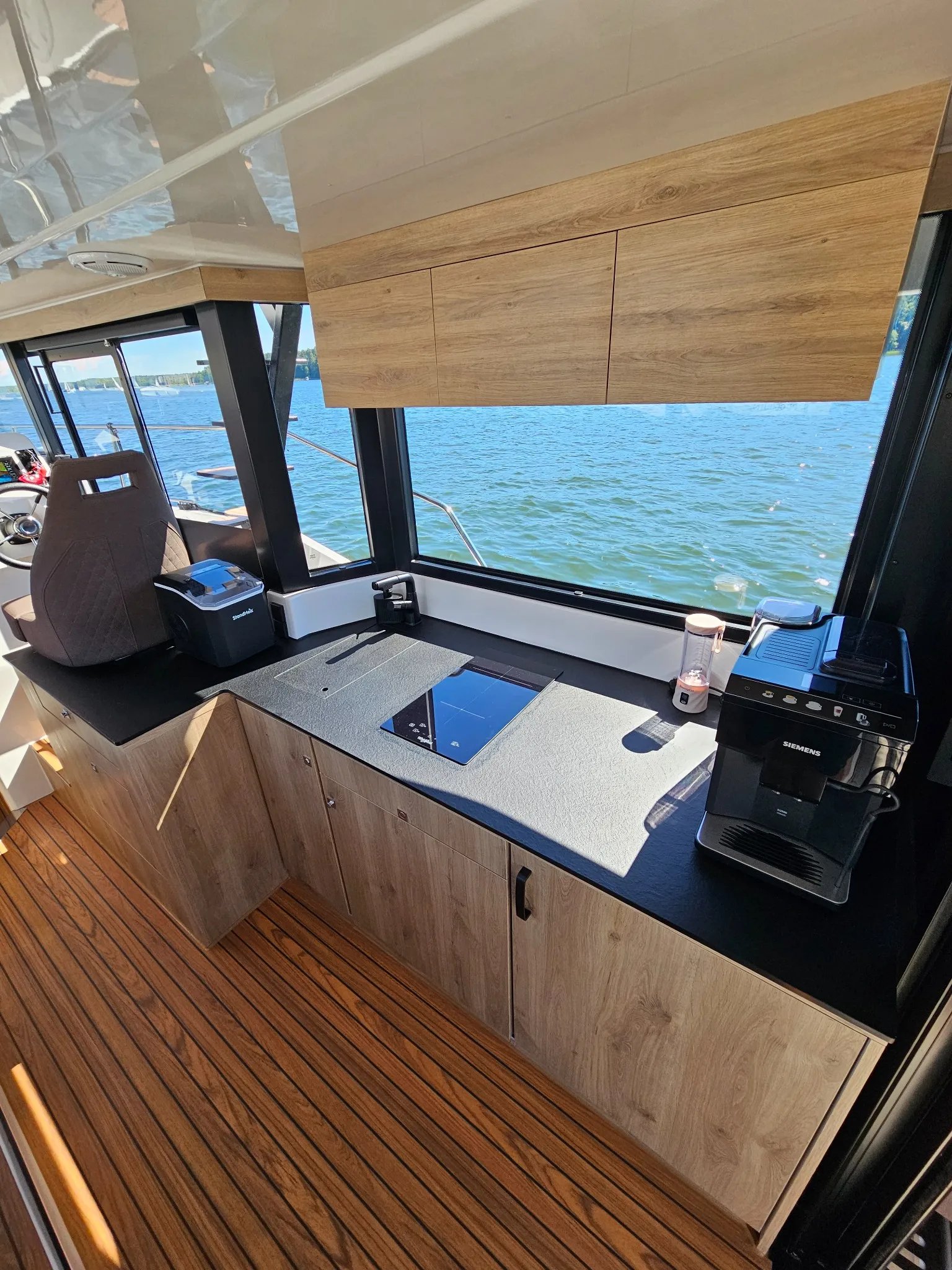 Galley of the Lamdo eLY30+ with induction cooktop, storage cabinets and water views.