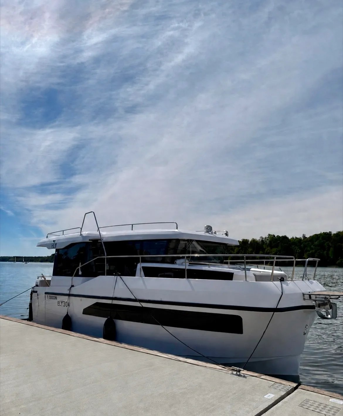 Side profile of the Lamdo eLY30+ electric houseboat moored in calm water.