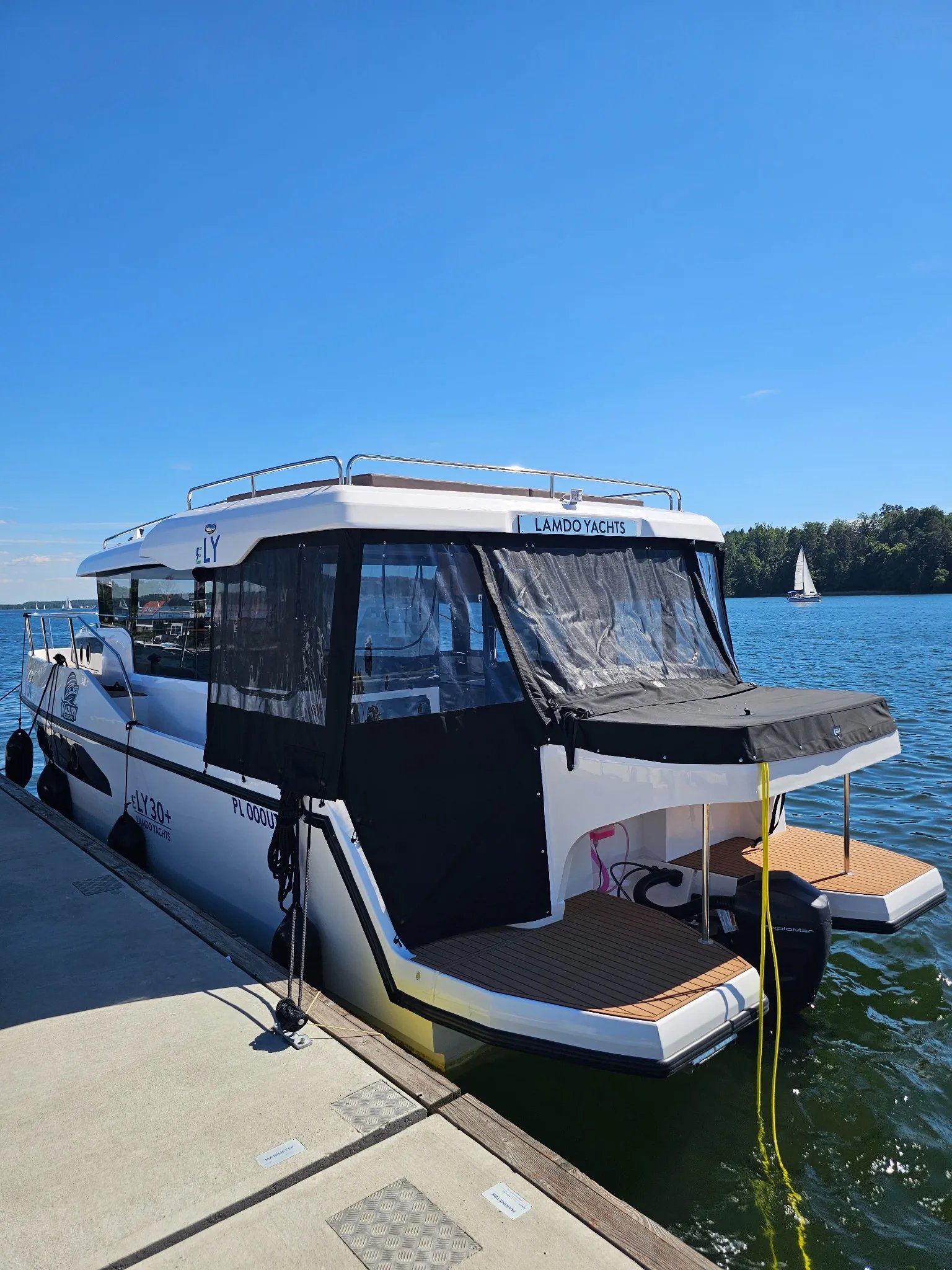 Rear three-quarter view of the Lamdo eLY30+ electric houseboat moored at a marina.