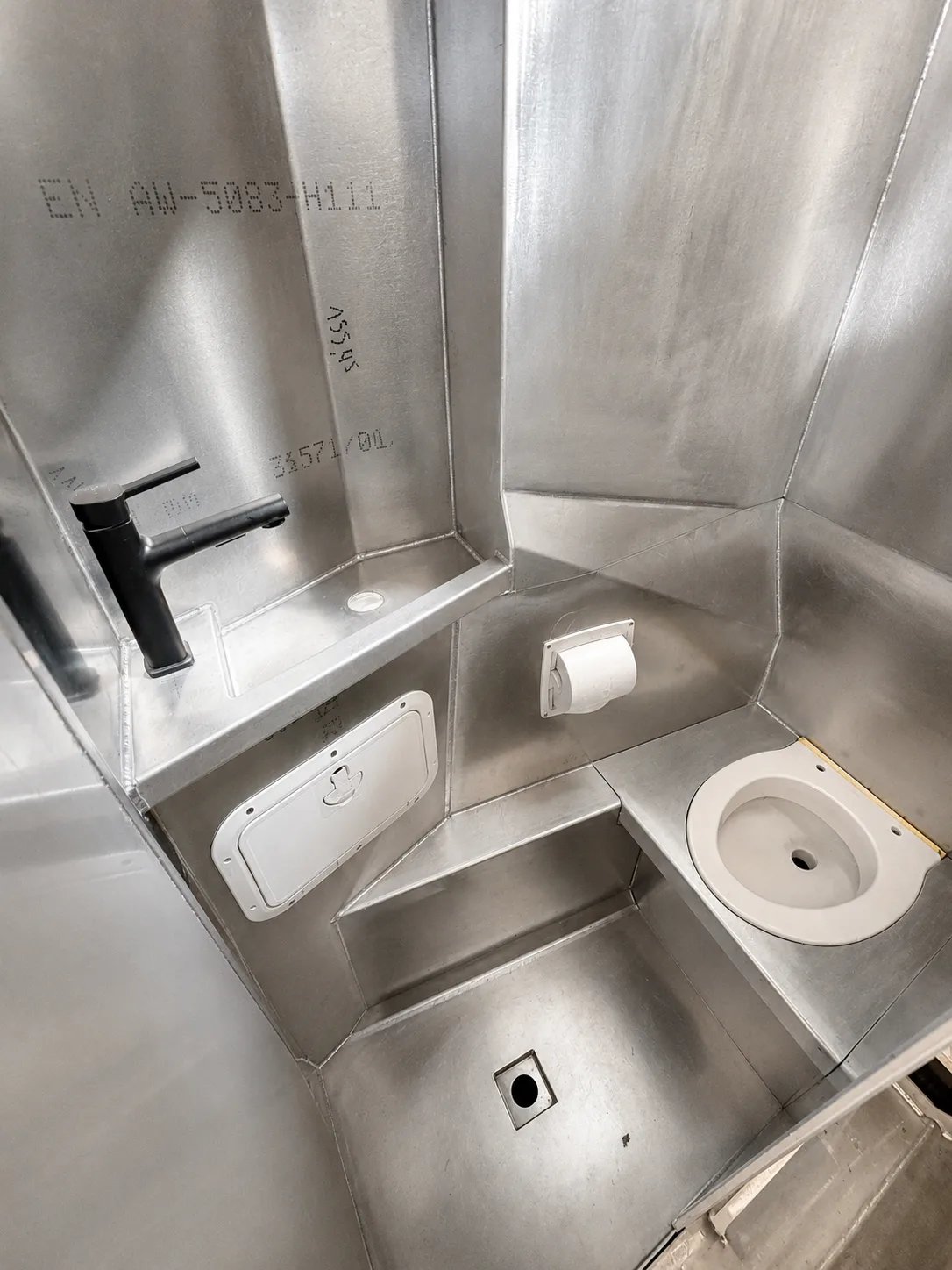 Compact all-aluminium bathroom aboard the Solann, with integrated washbasin, marine toilet and shower drain.
