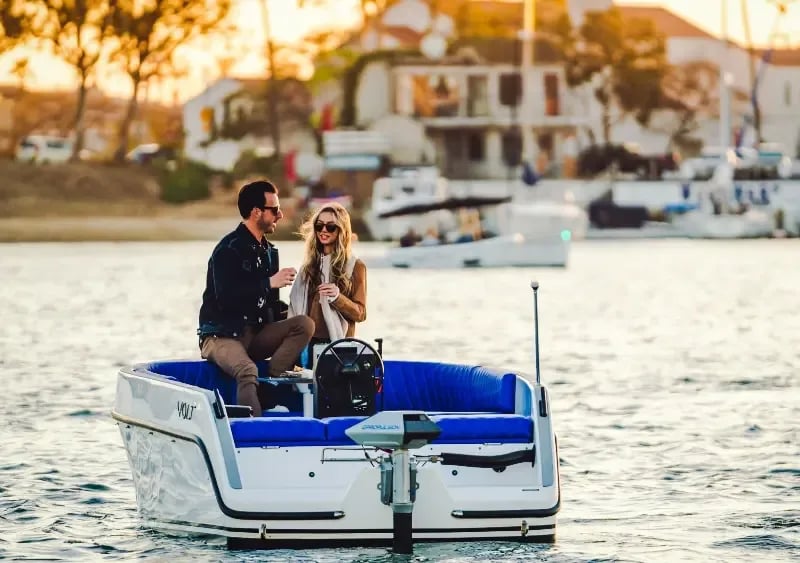 A blue and white boat with a man and woman on it.
