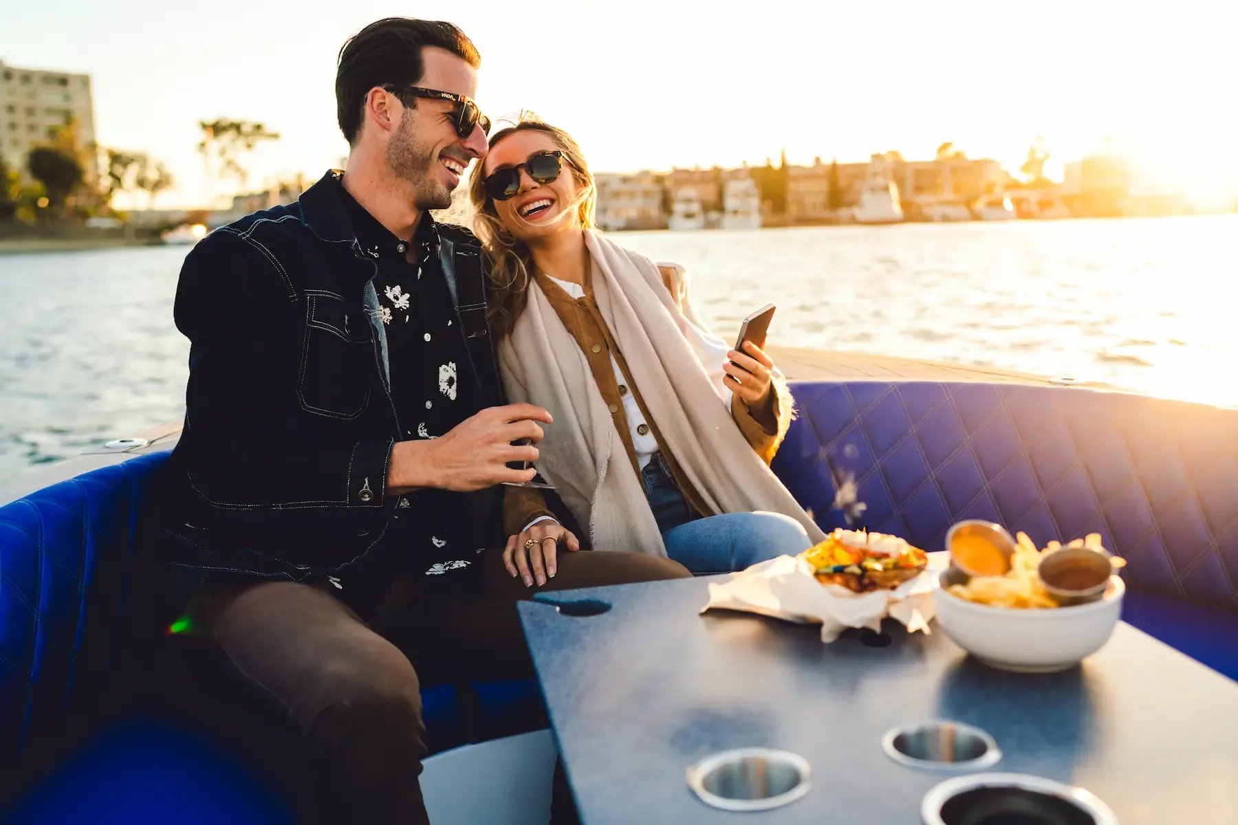 A man and woman are sitting on a boat with a bowl of food in front of them.