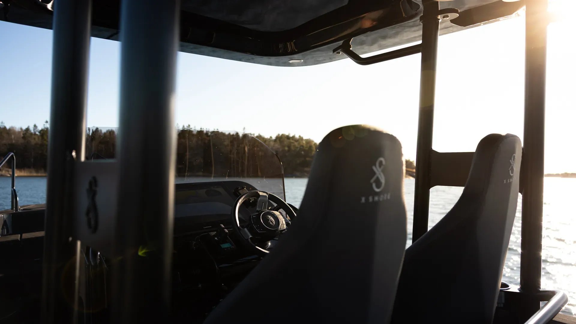Helm seats and steering console aboard the X Shore PRO at sunset