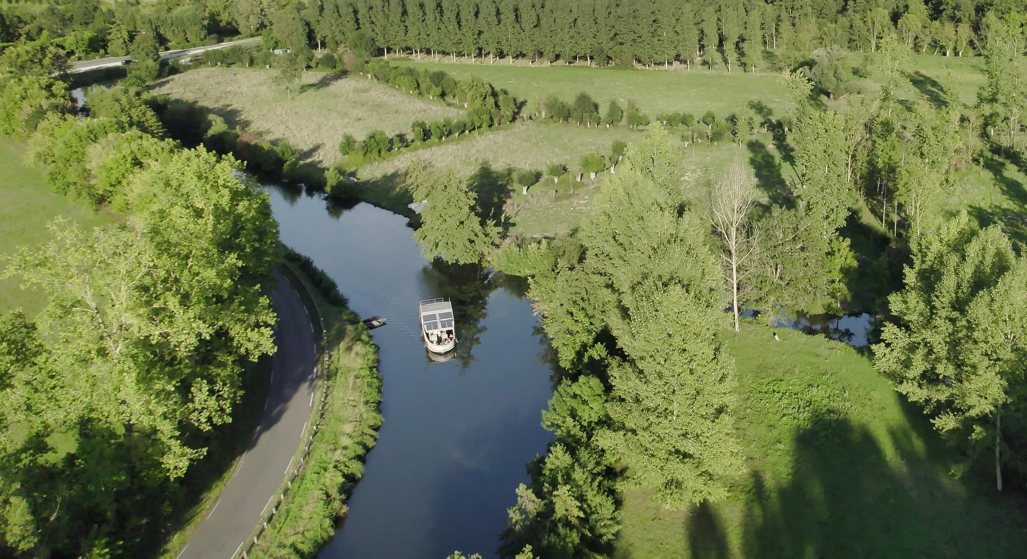 A small white boat with a green roof on a river.