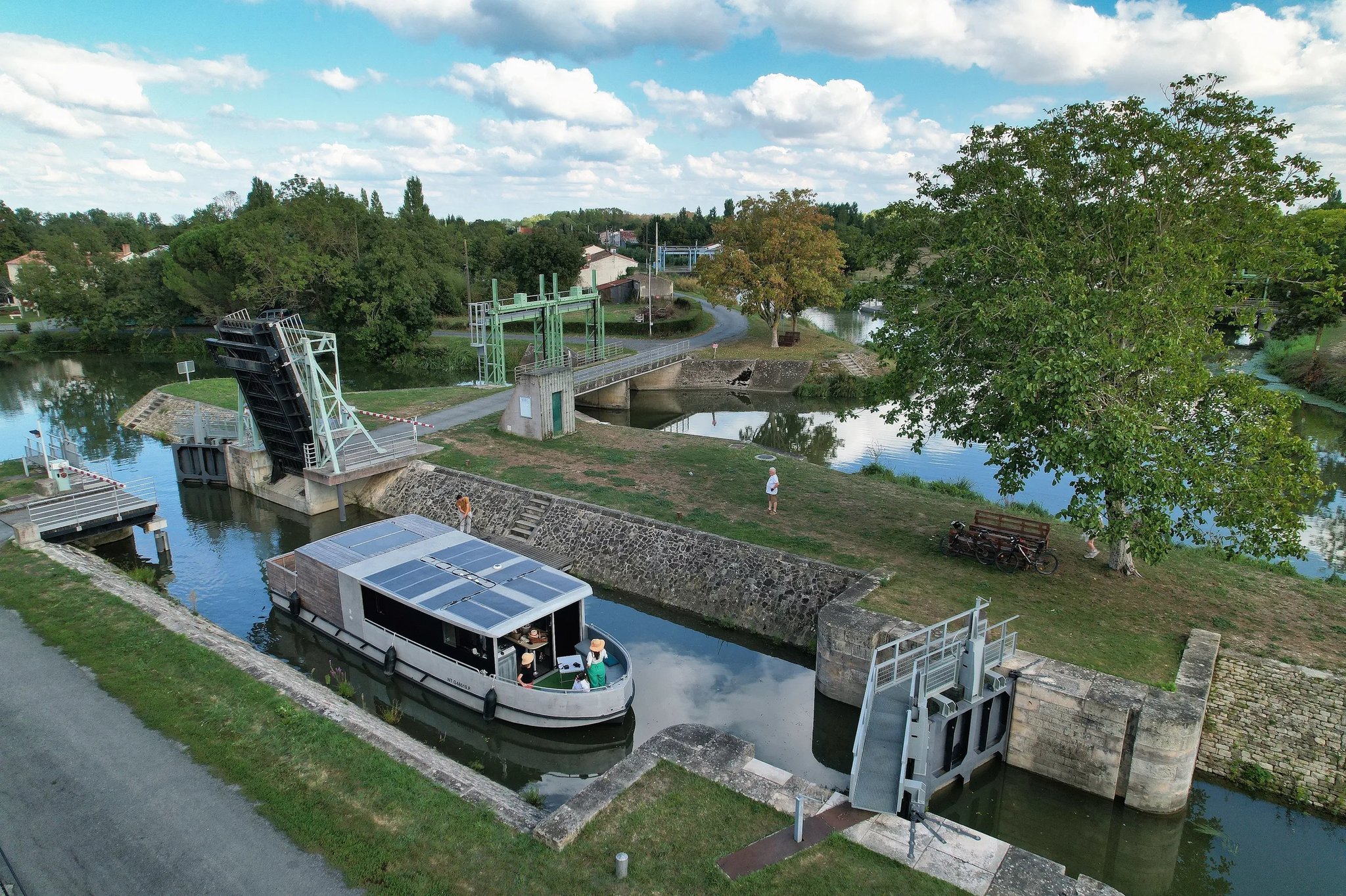 Zenriver solar electric houseboat passing through a canal lock and bascule bridge in the Marais Poitevin