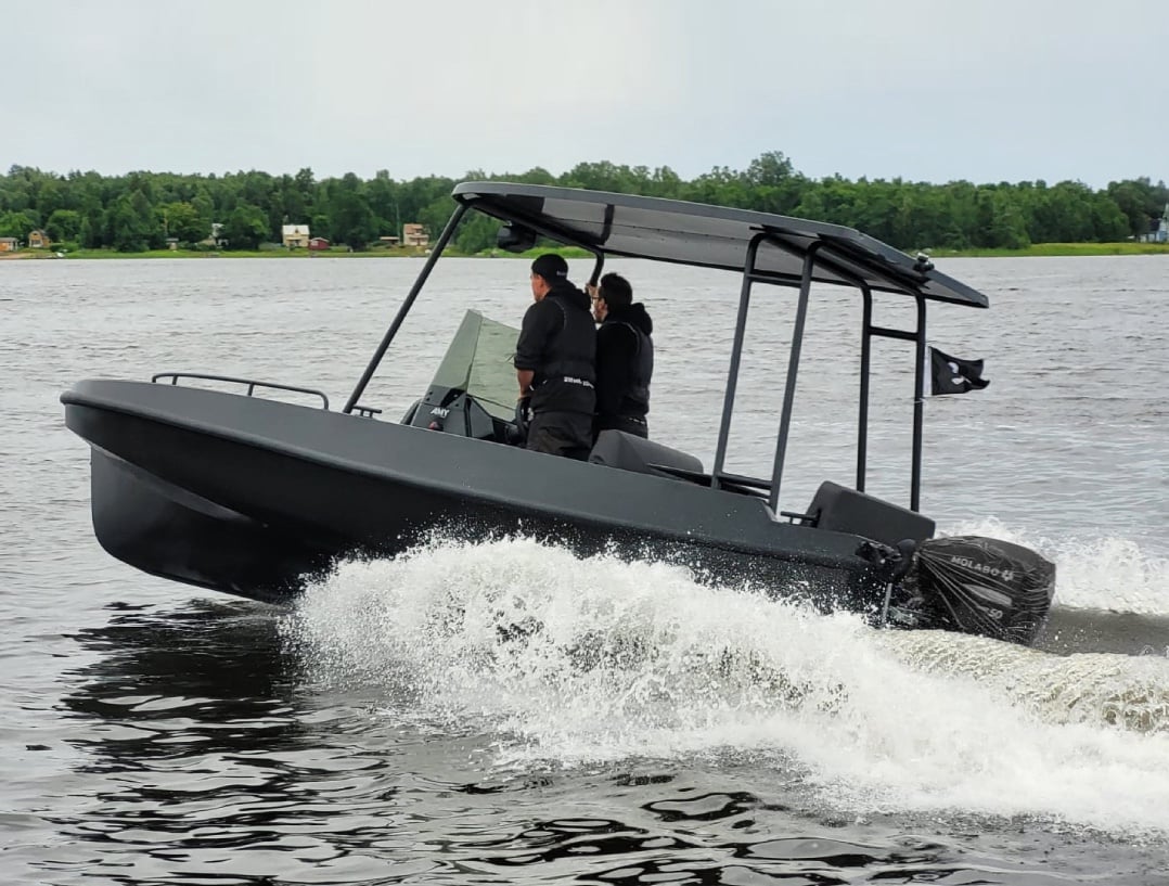 A black boat with three men on it.
