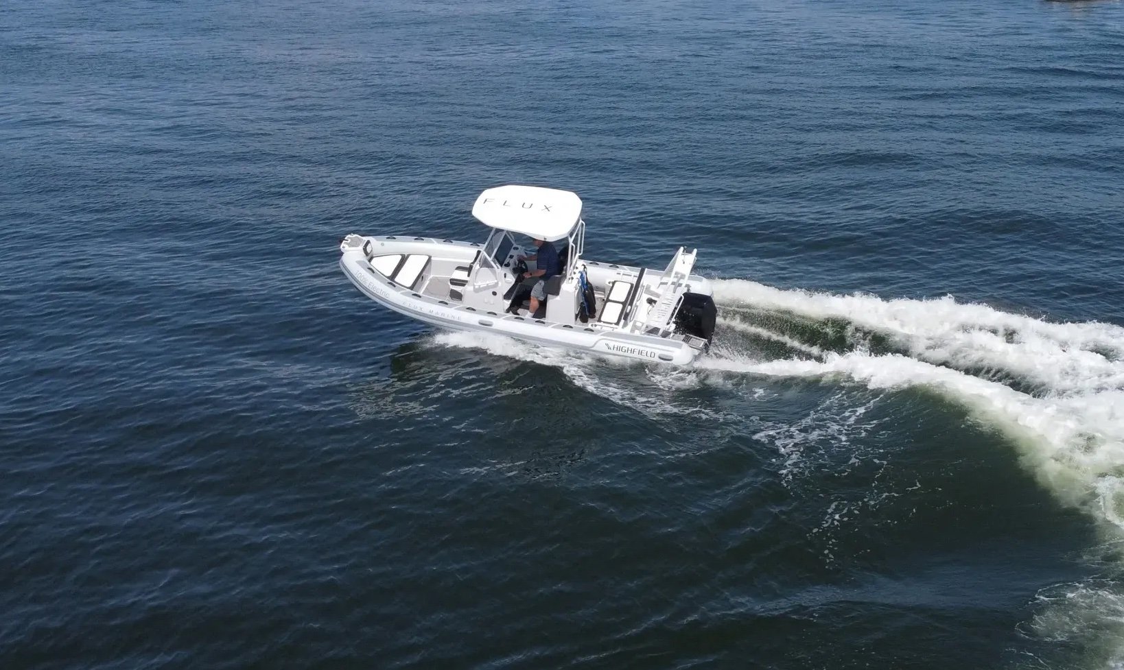 A white boat with a man in a blue shirt on it.