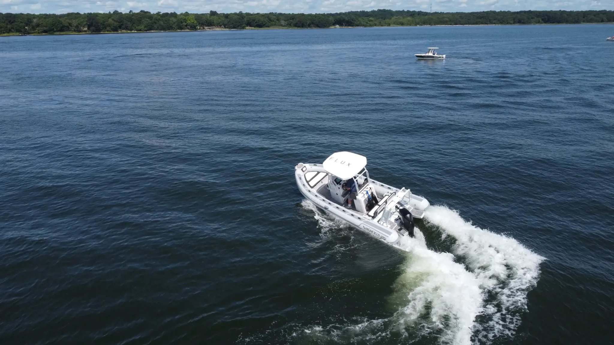 A white boat with a black top on the water.