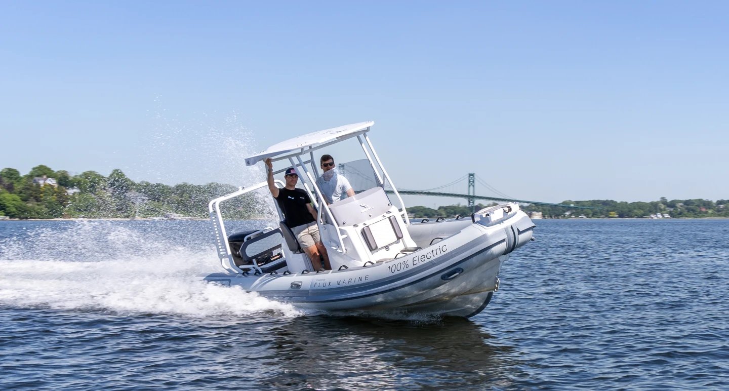 A boat with a man in a black shirt and a man in a blue shirt.