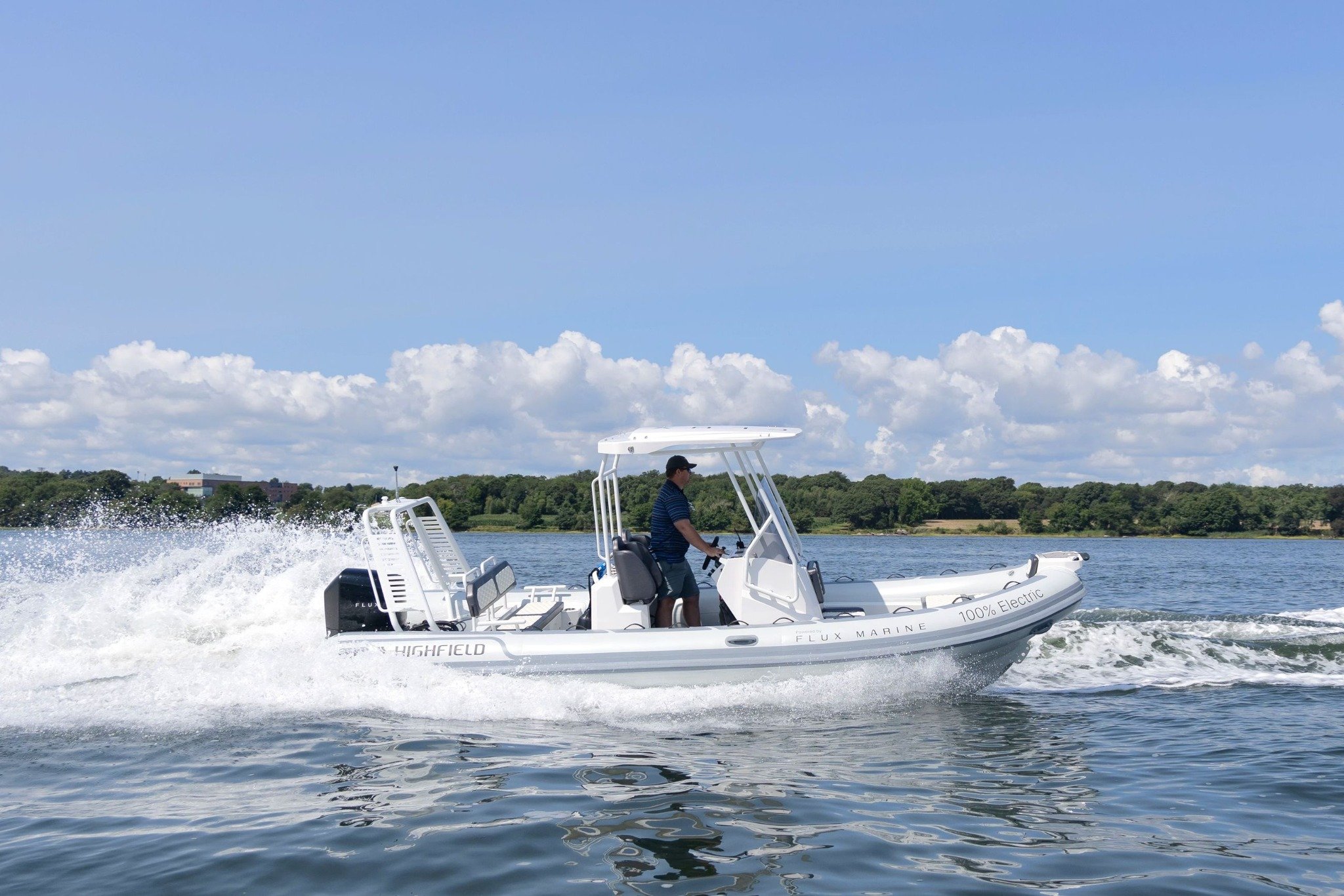 A white boat with a man in a blue shirt driving it.