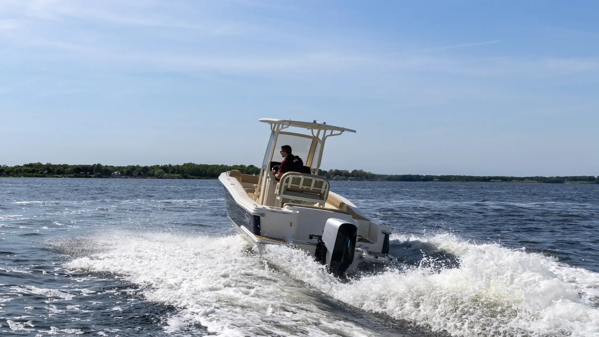 A man is driving a boat with a white top.